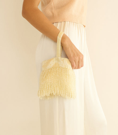 Person holding a champagne handbag against a plain background