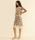 A woman models a matching set featuring a sleeveless top with a dense floral print in cream, pink, and green, finished with a cream lace hem, set against a solid cream background.